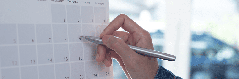 man's hand with silver pen making a note on a residency calendar